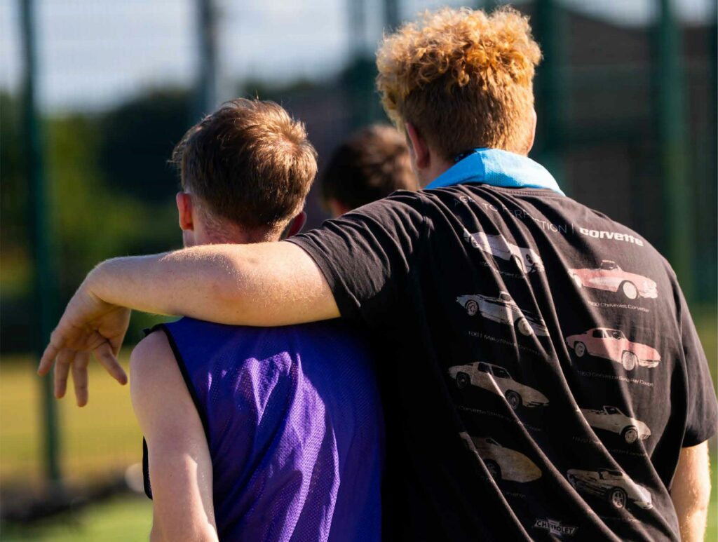 two boys walking, one has his arm around the other
