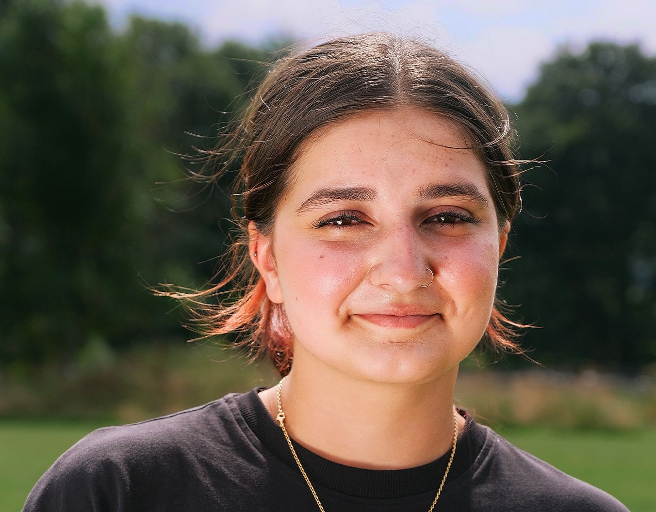 young woman stood outside smiling at the camera. The photo if of her head and choulders