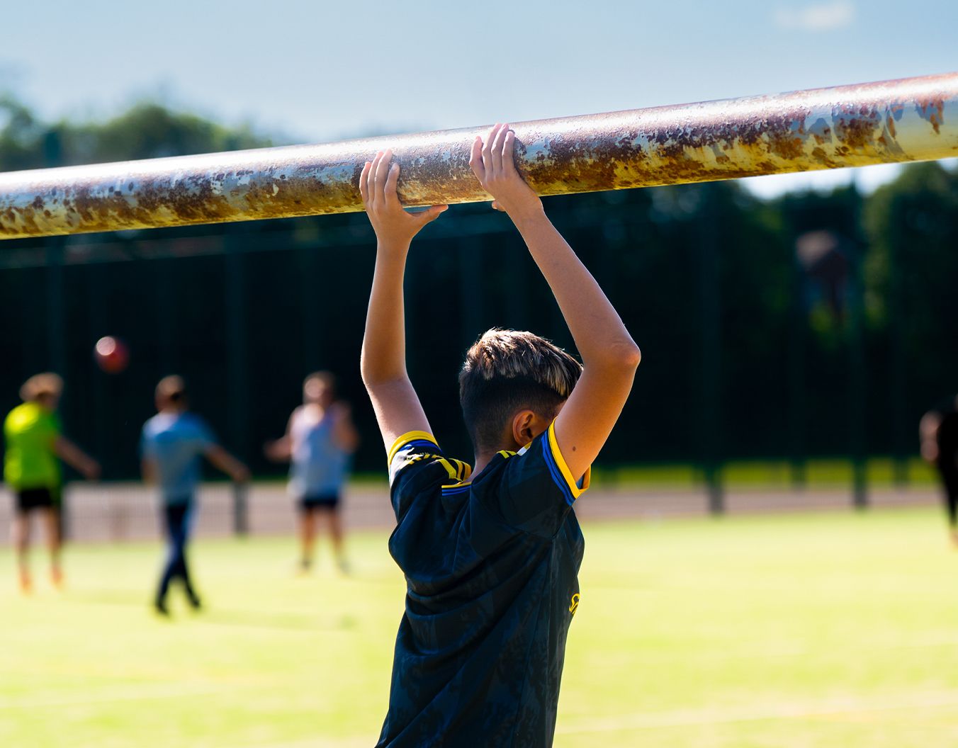 a boy stood in a goal with his arms on the top of the goals