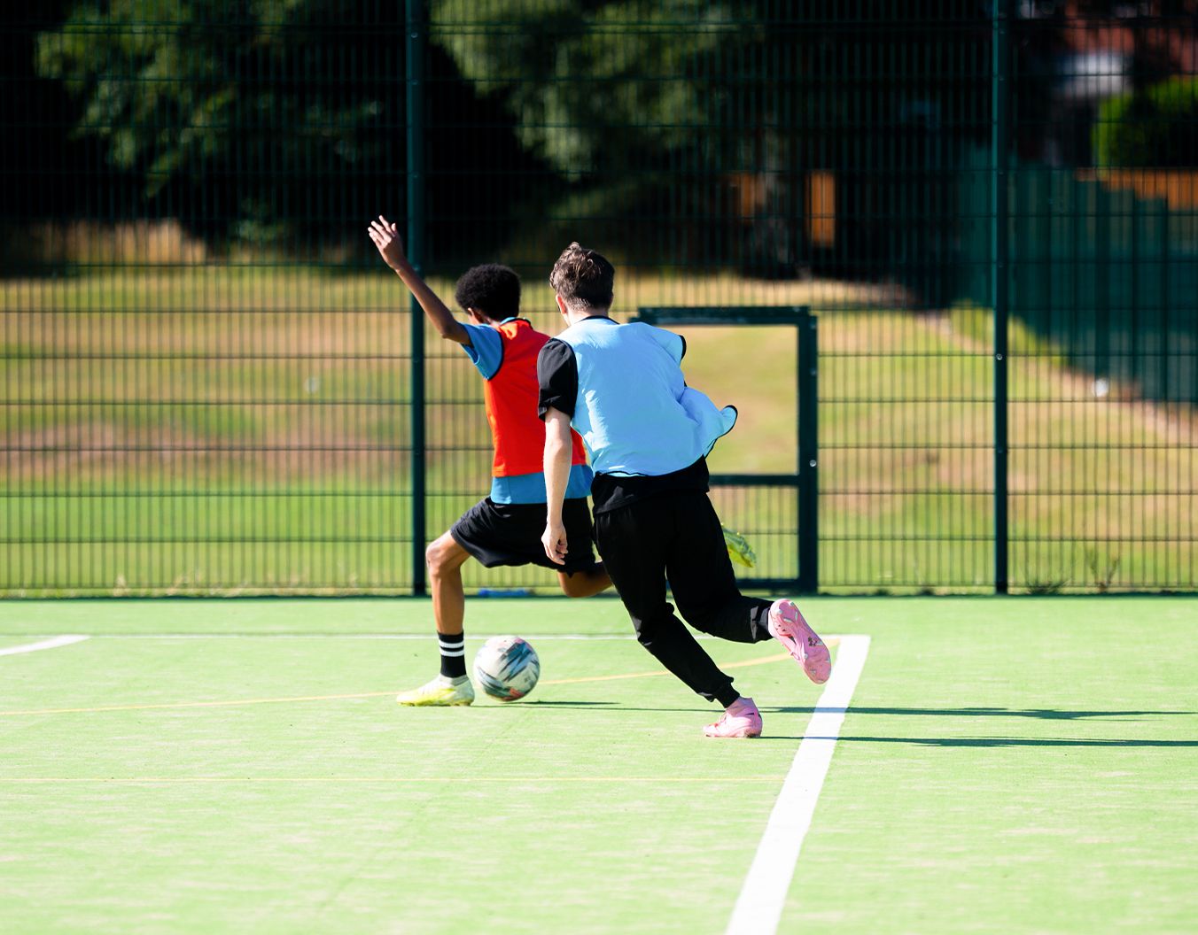 2 boys on a football pitch running for the football