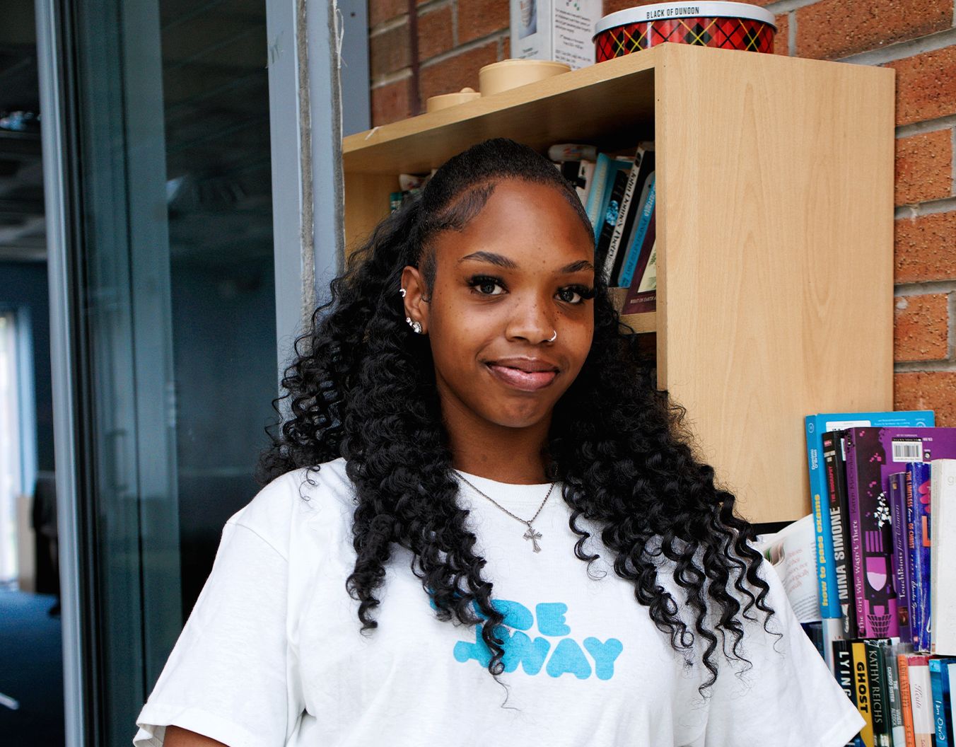 Young adult posing for the camera in front of a bookcase